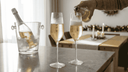 Twee flûtes met bruisende alcoholvrije bubbels en een gekoelde fles in een ijsemmer op een moderne eettafel